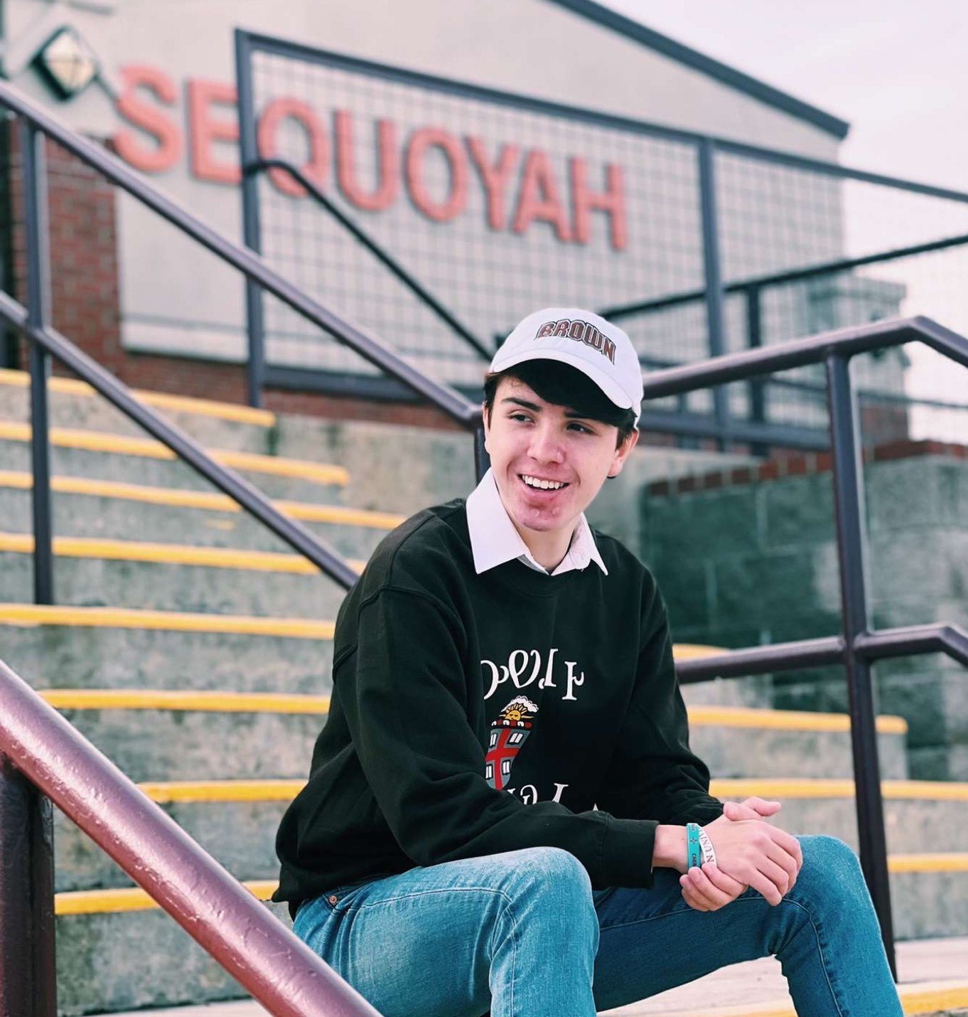 Anagali (Shace) Duncan smiles in Brown apparel at his high school athletic field. Sequoyah High School is a boarding school for indigenous students in grades 7-12. 