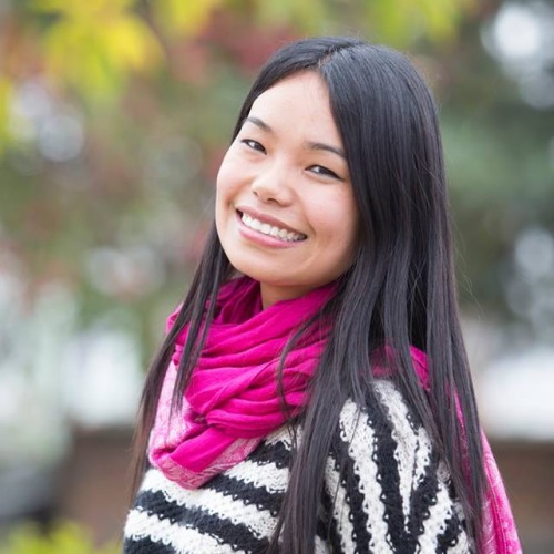 Sonam Sherpa smiles wearing a horizontally striped sweater and pink scarf 